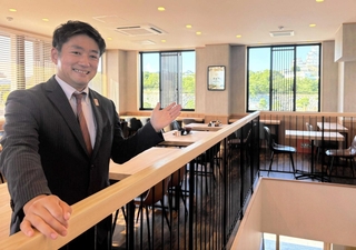 姫路城のすぐそばに新店をオープンした「まねき食品」の竹田典高社長。２階の窓からは大天守が見える＝姫路市本町