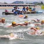 水しぶきを上げ、勢いよく泳ぎ出す参加者たち＝姫路市的形町、的形海水浴場沖