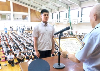 全校生徒の前で表彰を受ける福崎高校２年の志茂昊河さん＝福崎高校（姫路西消防署提供）