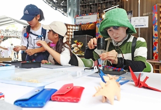 皮革製品のワークショップで、ミャクミャク色のブレスレットを手作りする参加者＝大阪市此花区の夢洲（撮影・辰巳直之）