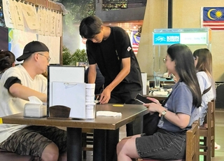 クアラルンプール市内の焼き鳥店「金の壺」で接客する姫路商業高校の生徒＝８月８日、マレーシア（同校提供）