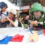 皮革製品のワークショップで、ミャクミャク色のブレスレットを手作りする参加者＝大阪市此花区の夢洲（撮影・辰巳直之）