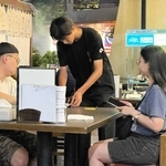 クアラルンプール市内の焼き鳥店「金の壺」で接客する姫路商業高校の生徒＝８月８日、マレーシア（同校提供）