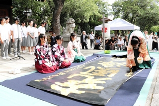 金色のカラー液で揮毫する高校生＝姫路護国神社