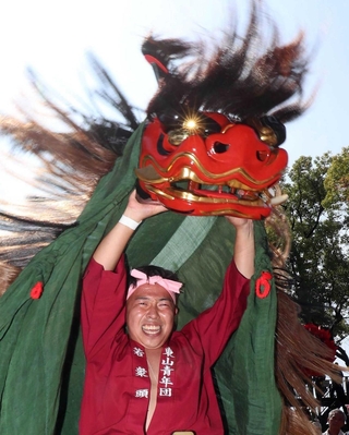 境内で獅子舞を披露する東山地区の氏子。獅子の目から陽光が差す（撮影・辰巳直之）＝松原八幡神社