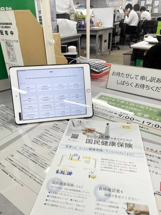 国民健康保険について外国人に配るチラシ（手前）と翻訳機になるタブレット端末＝姫路市役所