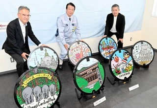スタンプラリーに向け、姫路の観光地をデザインしたマンホールをＰＲする「虹技」の山本幹雄社長（中央）ら＝姫路市大津区吉美