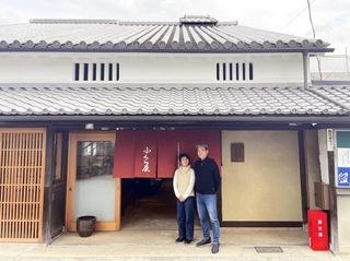 国登録有形文化財に答申された旧尾上家住宅の主屋。玄関先に立つ塩本さん夫婦が歴史的町家を守る＝姫路市堺町