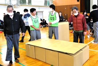 段ボール紙製の簡易ベッドを組み立てる生徒と地域住民＝姫路市網干区新在家、網干高校