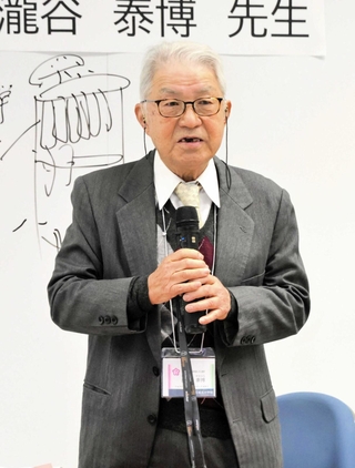 ８０年前の自身の小学生生活を６年生に語る瀧谷泰博さん＝城北小学校