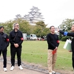 姫路フィルムコミッションの井上正也部長（右から２人目）から姫路城の解説を聞くハリウッド関係者＝姫路市本町