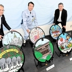 スタンプラリーに向け、姫路の観光地をデザインしたマンホールをＰＲする「虹技」の山本幹雄社長（中央）ら＝姫路市大津区吉美