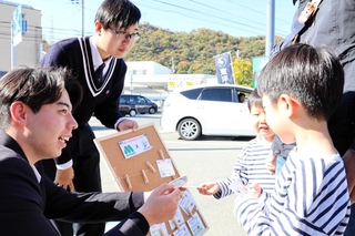 「お互いさまチケット」を子どもたちに手渡す東洋大付属姫路高校の生徒ら＝姫路市辻井３