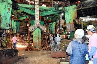 社員の説明を聞きながら、鎖の溶接工程を間近で見学する参加者＝姫路市網干区大江島、濱中製鎖工業網干工場