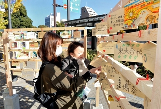 大手前通りの歩道に設置された絵馬掛けに絵馬を掛ける親子＝姫路市西二階町