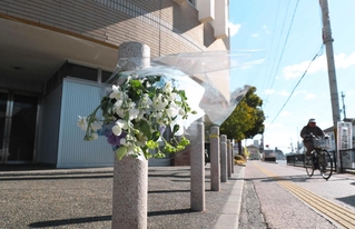 花束が手向けられている現場マンション前＝２２日午前、姫路市岩端町