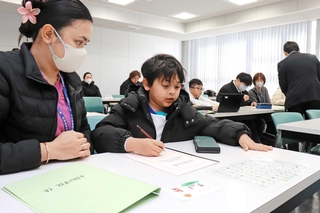 通訳のサポートを受けながら、日本語の初歩を学ぶ子どもたち＝姫路市北条口３