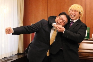 プロレスラーの望月ジュニア選手（右）にヘッドロックをかけられて喜ぶ姫路市の清元秀泰市長＝姫路市役所