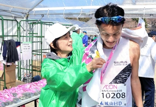 完走者に記念タオルをかけるボランティアスタッフ＝姫路城三の丸広場