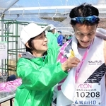 完走者に記念タオルをかけるボランティアスタッフ＝姫路城三の丸広場