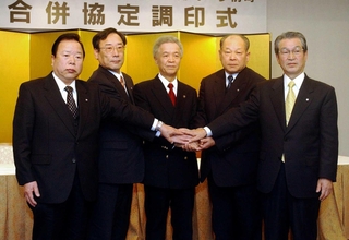 合併調印を終え、手を重ねる姫路市の石見利勝市長（中央、当時）と周辺４町の首長ら＝２００５年２月、姫路市内のホテル