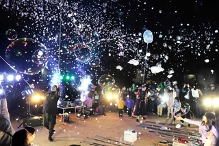 児童の卒業を祝って夜空に飛ばされたシャボン玉＝手柄小学校