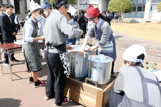 かまどに変身した防災ベンチで温めた豚汁をふるまう生徒ら＝姫路商業高校