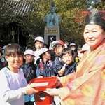 河合寸翁の銅像の前で、集めた修復費を神崎歩宮司（右）に手渡す児童＝姫路市本町、姫路神社