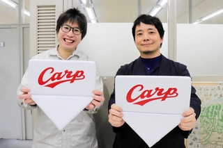 プロ野球広島東洋カープの公式グッズに採用された澤田棉行のホームベース型クッションと、同社の澤田尭社長（右）＝姫路市西今宿３