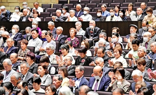 来賓のあいさつに拍手で応える金婚夫婦祝福式典の参加者＝姫路市神屋町、アクリエひめじ