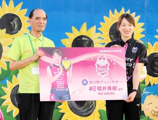市川町の津田義和町長から委嘱状代わりのパネルを受け取るヴィクトリーナ姫路の桜井美樹選手＝市川町文化センター