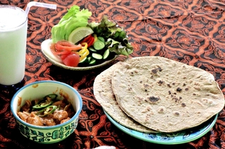 パキスタン料理の（右手前から時計回りに）ロティ、チキンカラヒ、ラッシー、サラダ