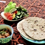 パキスタン料理の（右手前から時計回りに）ロティ、チキンカラヒ、ラッシー、サラダ