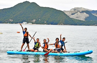 家高名物の海洋スポーツ大会。海に飛び込んだ後、「メガＳＵＰ」の上で笑顔を見せる生徒＝姫路市家島町真浦