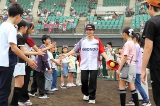 ソフトボールの始球式に登場した坂本花織さん（中央）とタッチを交わす子どもたち＝姫路市飯田、ウインク球場