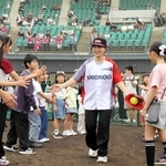 ソフトボールの始球式に登場した坂本花織さん（中央）とタッチを交わす子どもたち＝姫路市飯田、ウインク球場