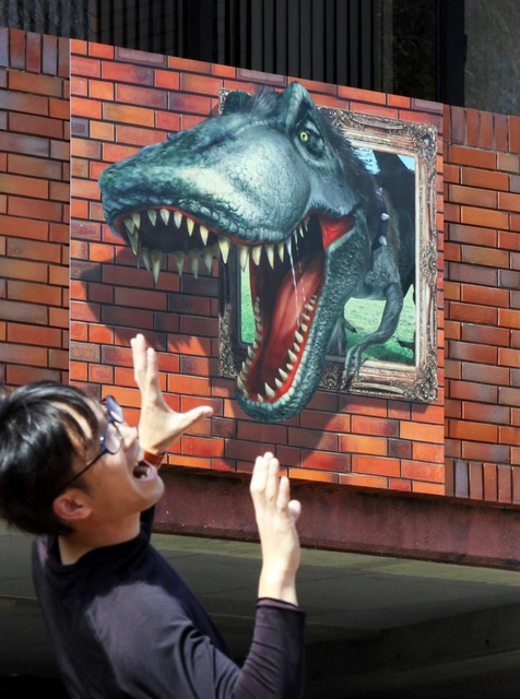 壁面から恐竜が飛び出すように見える看板のだまし絵＝加東市下滝野