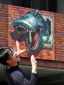 壁面から恐竜が飛び出すように見える看板のだまし絵＝加東市下滝野