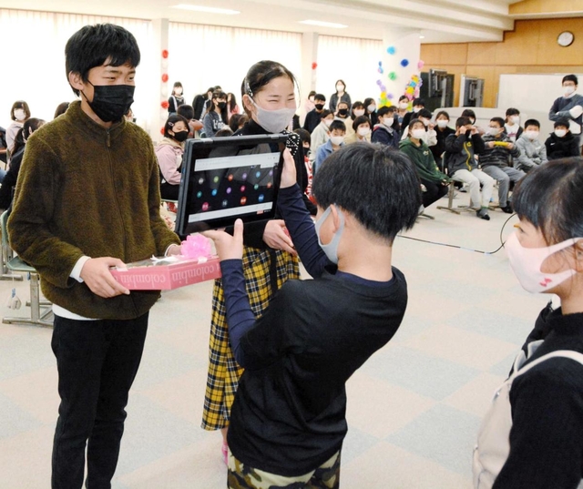 下級生からプレゼントを受け取り、タブレットを通じて感謝の言葉を伝える６年生の児童＝多可町八千代区中野間