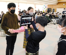 下級生からプレゼントを受け取り、タブレットを通じて感謝の言葉を伝える６年生の児童＝多可町八千代区中野間