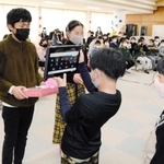 下級生からプレゼントを受け取り、タブレットを通じて感謝の言葉を伝える６年生の児童＝多可町八千代区中野間