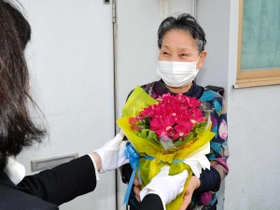 笑顔で花の鉢植えを受け取る高齢者＝西脇市内