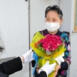 笑顔で花の鉢植えを受け取る高齢者＝西脇市内