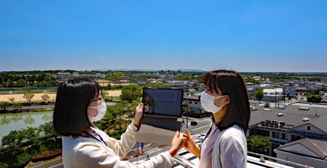 加東市の特徴の一つ、広い空の下、タブレットを使い市街地をテスト撮影する市職員＝加東市社から