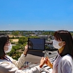 加東市の特徴の一つ、広い空の下、タブレットを使い市街地をテスト撮影する市職員＝加東市社から