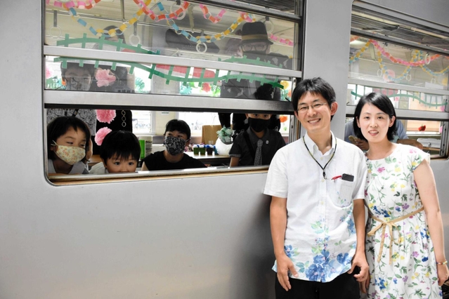 友人たちが飾り付けた車内で披露宴を開いた佐柄忠憲さん、睦子さん＝加西市北条町北条、北条町駅