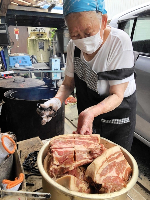 たれに漬け込んだ豚肉を窯に移す飛田春子さん＝西脇市黒田庄町喜多「日の出精肉店」