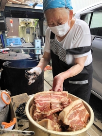 たれに漬け込んだ豚肉を窯に移す飛田春子さん＝西脇市黒田庄町喜多「日の出精肉店」