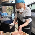 たれに漬け込んだ豚肉を窯に移す飛田春子さん＝西脇市黒田庄町喜多「日の出精肉店」