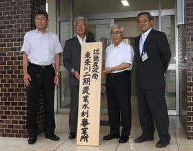 事業所の看板を手にする関係者ら＝加東市社